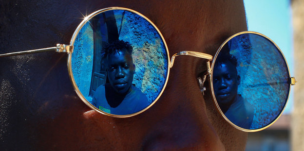 Eine Sonnenbrille, in der sich ein Flüchtling spiegelt