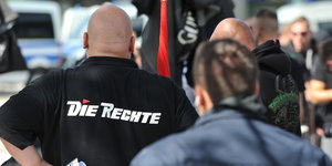 Ein Mann mit einem Hemd mit der Aufschrift "Die Rechte" steht vor einem Polizisten