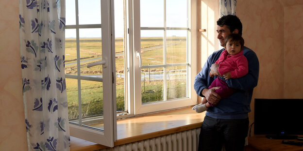 Ein Mann mit Kind steht an einem Fenster