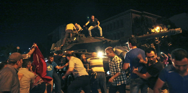 Eine Gruppe Demonstranten besetzt einen Militärpanzer