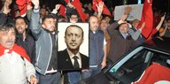 Jubelnde Männer mit Türkei-Fahen und einem Foto von Präsident Erdogan
