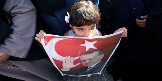 Ein kleines Mädchen hält ein Bild von Erdogan mit der türkischen Fahne hoch