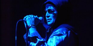 Alan Vega im Halbdunkel an einem Mikrofon