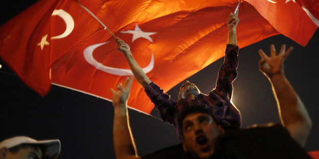 Männer schwenken türkische Flaggen. Es ist dunkel