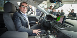 Verkehrsminister Dobrindt sitzt in einem Auto, durch die Scheiben sind Fotografen zu sehen