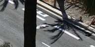 Der Schatten einer Palme fällt auf eine Straße, darauf liegt ein weißes Tuch