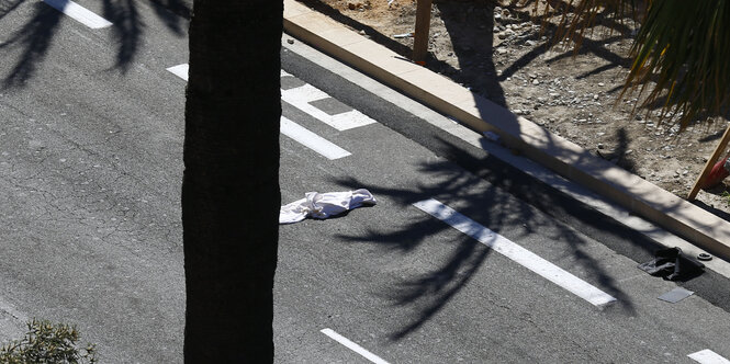 Der Schatten einer Palme fällt auf eine Straße, darauf liegt ein weißes Tuch