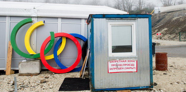 Hütte mit Schild "Verbotene Zone", an der Wand lehnen die olympischen Ringe