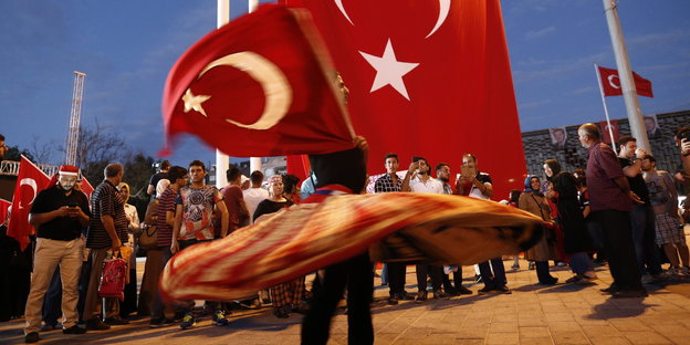 Ein Mann hält eine türkische Fahne und lässt seinen rot-weißen Rock kreisen