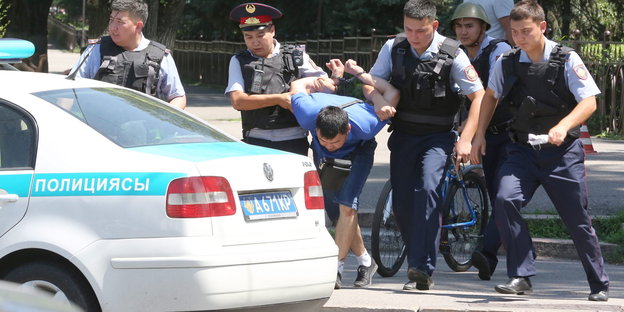 Kasachische Polizisten nehmen einen Mann fest