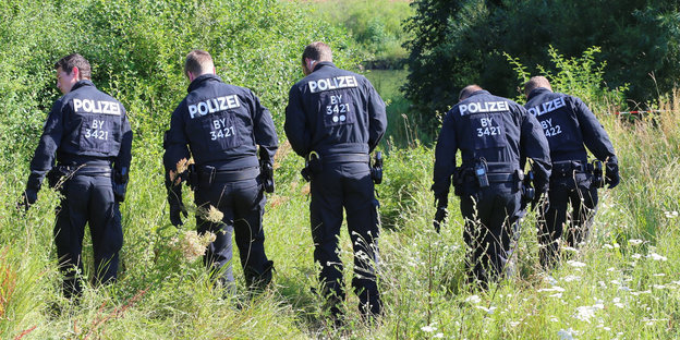 Polizisten suchen in Würzburg auf einer Wiese nach Spuren