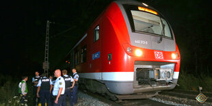 Es ist Nacht, vor einem Regionalzug stehen Polizisten