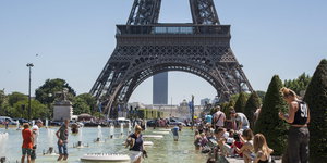 Ein Sommertag: Vor dem Eiffelturm in Paris planschen Menschen im Wasser oder halten ihre Füße hinein