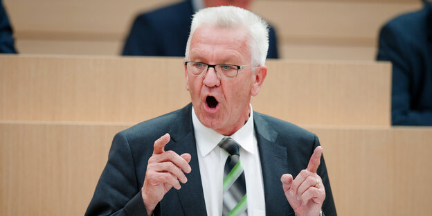 Winfried Kretschmann mit offenem Mund und erhobenen Zeigefingern während einer Rede