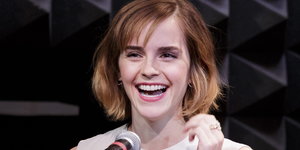 Eine junge Frau mit kurzen Haaren vor einem Mikrofon lacht
