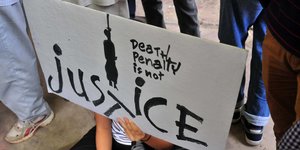 Jemand hält ein Protestschild zur Todesstrafe hoch