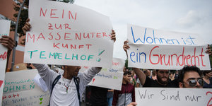 Flüchtlinge halten am 11.07.2016 bei einer Demonstration in Berlin-Neukölln Schilder mit der Aufschrift "Nein zur Massenunterkunft Tempelhof" und "Wohnen ist ein Grundrecht". Mit der Aktion protestieren die Flüchtlinge gegen ihre geplante Unterbringung in