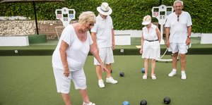 Vier Rentner in weißer Kleidung spielen ein rätselhaftes britisches Spiel mit Kugelb
