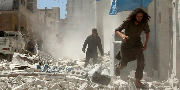 Männer rennen durch von Luftangriffen zerstörte Straßen in Syrien