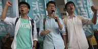 Die Studentenaktivisten Joshua Wong (l.), Nathan Law und Alex Chow (r.) heben vor dem Gericht in Hongkong kämpferisch die Fäuste