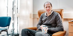 Der Wissenschaftler Nick Bostrom sitzt in einem Sessel und hält eine Tasse fest