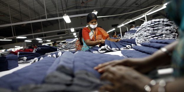 Eine Frau mit Atemschutz arbeitet in einer Textilfabrik