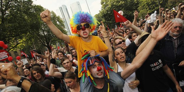 Menschen demonstrieren, einige als Clowns verkleidet