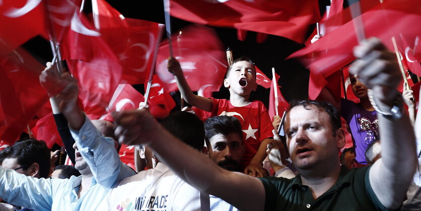 Menschen schwenken türkische Flaggen. Es ist Nacht.