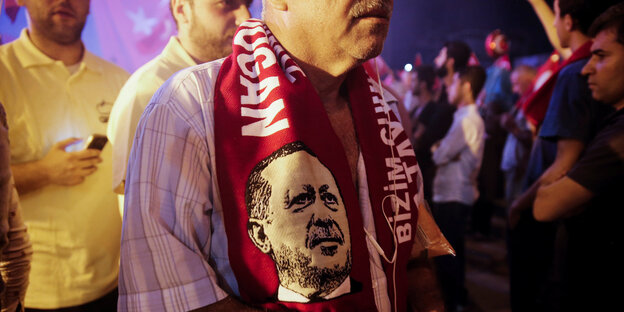 Mann mit einem Fan-Schal um die Schultern, darauf der türkische Präsident Erdogan