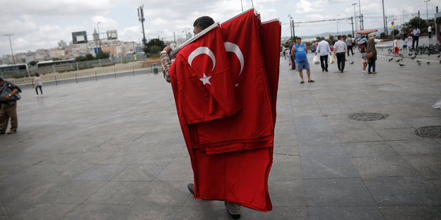 Ein Verkäufer trägt mehrere türkische Flaggen über einen Platz