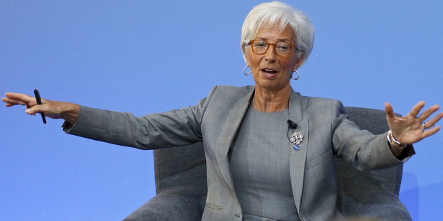 Lagarde mit weit ausgebreiteten Armen vor blauem Hintergrund