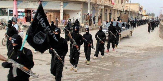 IS-Kämpfer in schwarzer Kleidung laufen in einer Reihe