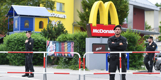 Polizeibeamte stehen an Absperrungen vor einer McDonald`s Filiale