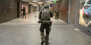Ein paar Polizisten in Schutzkleidung in einem Münchner U-Bahnhof