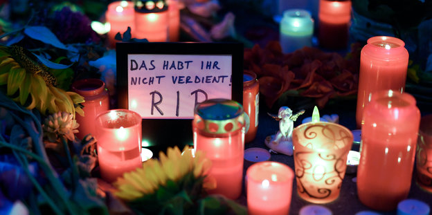 Blumen, Kerzen und ein Schild mit der Aufschrift "R.I.P., Das habt ihr nicht verdient"