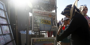 Eine Frau steht neben einem Ständer mit türkischen Zeitungen
