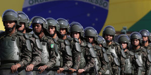 Soldaten marschieren vor einer übergroßen brasilianischen Flagge