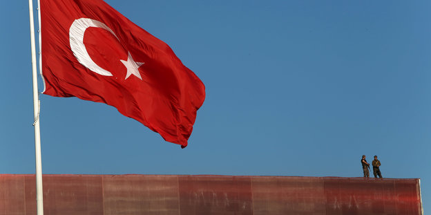 Die türksiche Flagge und Polizisten auf einem Dach