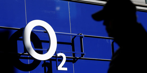 Weißer O2-Schriftzug auf blauem Grund, daneben im Vordergrund der Schatten eines Mannes