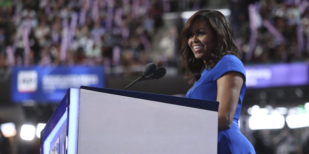 Eine Frau vor einem Pult. Es ist Michelle Obama