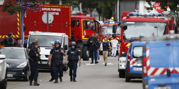 Französische Polizisten und Feuerwehrmänner kommen vor der Kirche in Saint-Etienne-du-Rouvray an