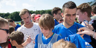 Mehrere Fußballspieler des Hamburger SV umringt von Fans und Autogrammsammlern