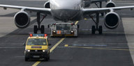 Ein gelber Kleinbus fährt auf einer Landebahn, dahinter ein Flugzeug