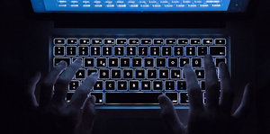 Hände tippen auf eine Tastatur im Dunkeln