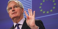 Michel Barnier mit erhobener Hand vor einer EU-Flagge