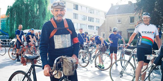 Ein älterer Mann mit Retro-Fahrrad, dahinter weitere Radsportler