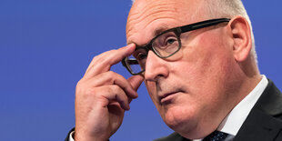 Frans Timmermans fasst sich an die Brille (Nahaufnahme)