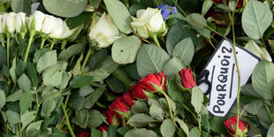 Blumen, dazwischen ein Schild auf dem „pourquoi“ steht