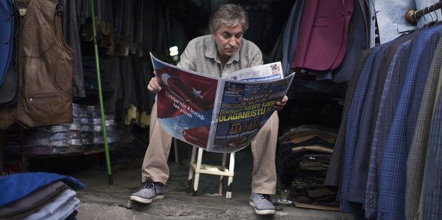 Ein Mann vor einem Laden liest Zeitung