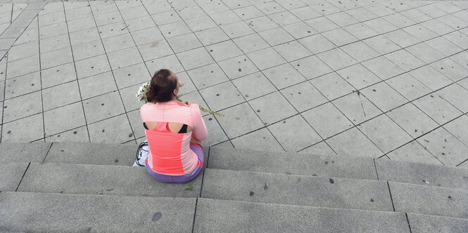 eine Frau mit Blumen in der Hand sitzt auf einer Treppe